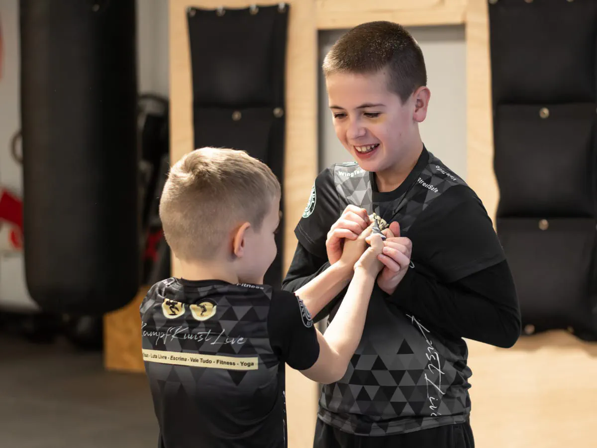 Zwei Jungen im Probetraining üben lachend eine Befreiung aus einem Griff