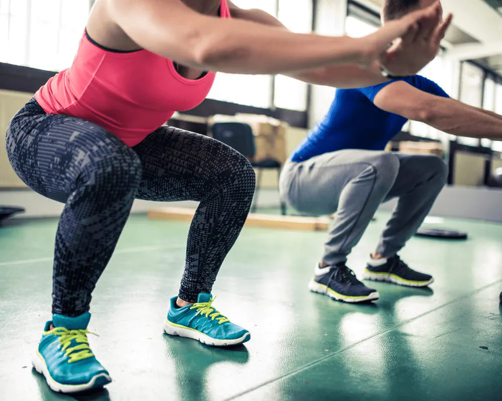 Zwei Personen machen beim Fitnesstraining Kniebeugen